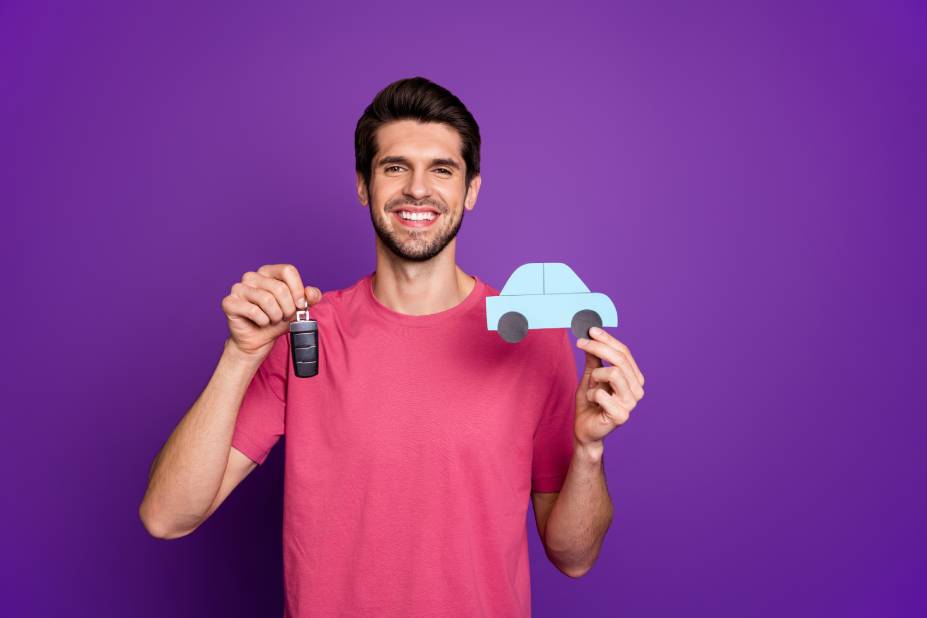 Jeune homme avec une petite voiture dans les mains content de son assurance auto